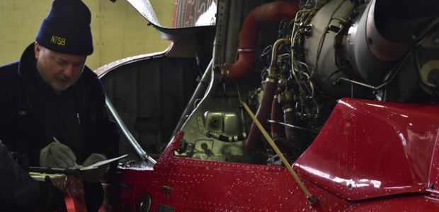 On March 13, 2018, Harald Reichel, an aerospace engineer with NTSB’s Office of Aviation Safety, examines the engine of the  Liberty Helicopters helicopter that crashed in the East River on March 11. (NTSB Photo by Chris O’Neil)