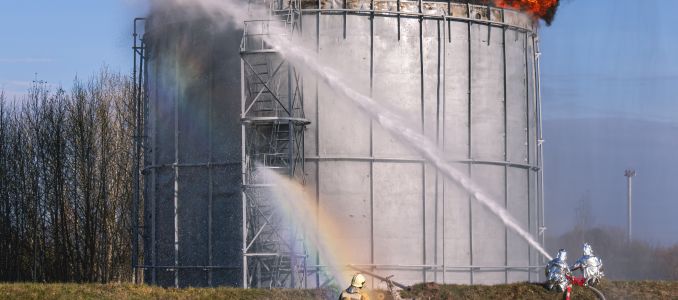 Firefighter Spray Water on Storage Tank Fire