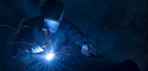 welder in mask welding, with blue sparks coming off object