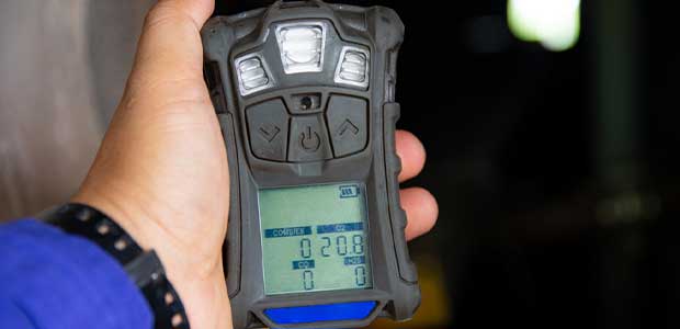 person with blue sleeve holding unlabeled gas detector