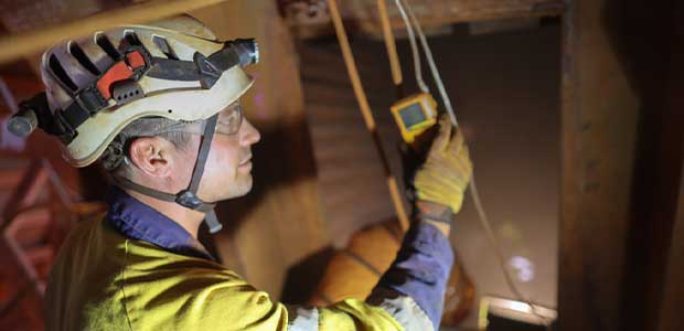 man with a hardhat checking a gas detection monitor 